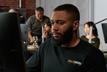 Paul Davis Restoration staff member working at a computer with colleagues in the background